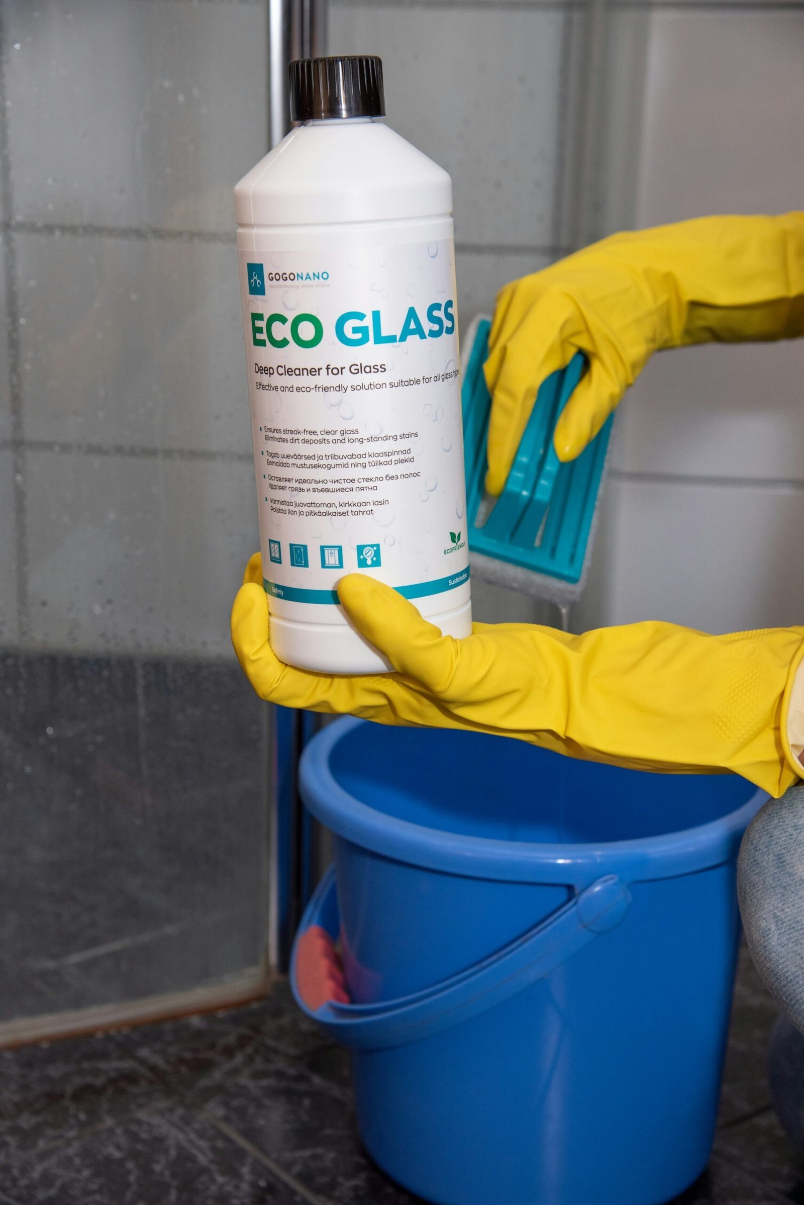 A person in yellow gloves and rubber gloves cleaning a bucket